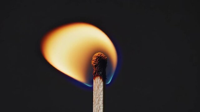 Burning matchstick with bright flame, close-up macro shot. Energy and ignition concept
