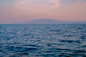 Fototapeta premium Seascape sunset with mountains on the horizon