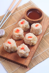 chicken dimsum served in a plate with chopstick and sauce