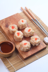 chicken dimsum served in a plate with chopstick and sauce