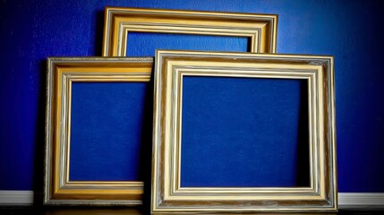 Fototapeta premium Set of three elegant decorative picture frames against a deep blue wall in artistic interior design setting