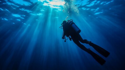 Diver ascends, sunbeams underwater, ocean background, scuba diving stock photo