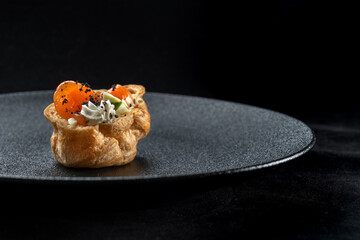 Fresh golden profiterole with pieces of red fish, salad and cream.