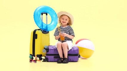 Girl sitting on suitcase drinking juice with a playful straw, smiling while enjoying travel vibes...