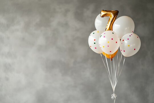 Golden number seven balloon with white and polka dot balloons against gray background