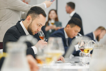 Beginner wine waiter sniffs alcoholic drink during blind tasting. Sommelier school, international...