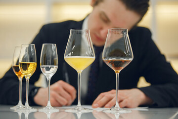Sommelier makes notes on the tasting card. Blind tasting of various alcoholic beverages, close up.