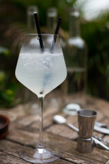 White cocktail with ice in a glass with a stem on a wooden surface