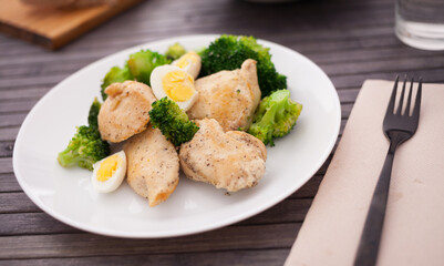 Chicken breast with broccoli and quail eggs on plate for healthy dinner