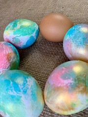 Decorative eggs in vibrant colors are arranged in a circular formation around a single brown egg, creating a festive atmosphere perfect for spring celebrations or Easter activities