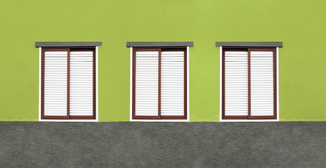 Three windows in a row. House closed shutters. Window shutters background. Green home wall facade. Architecture texture. Red window frame. Wooden stripes window cover. European style panoramic design.