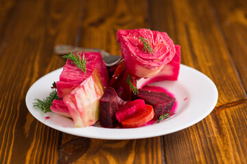 pickled cabbage with beets and carrots, in a plate, on a wooden table