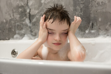 A relaxed child enjoying a bubble bath with eyes closed and hands on the face. A peaceful and calming moment of childhood, self-care, and relaxation. Soft foam and cozy atmosphere.