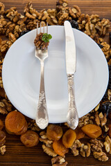 Clean empty plate with healthy dried fruits and nuts with antique cutlery
