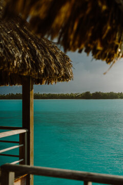 Luxurious overwater bungalow with thatched roof, offering a breathtaking ocean view in Bora Bora. Tranquil retreat with tropical decor, cozy bedding, and a serene island ambiance