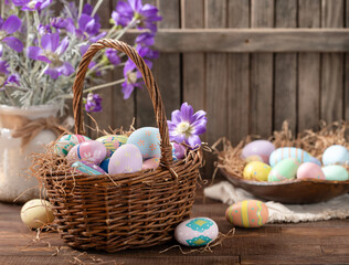 Easter eggs in a basket and bowl with purple daisies