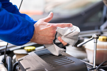 Close-up of technician working in car shop wipes hands with rag