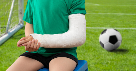 Close-up of a child soccer player suffering from a broken hand with a cast on the field