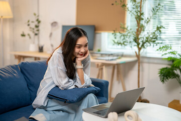 Obraz premium A woman is sitting on a couch with a laptop in front of her