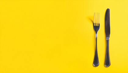 Black metal knife and fork isolated on yellow background. Flat lay.