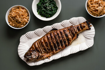 Charcoal grilled trout with noodles and spinach.