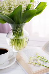 Spring composition with bouquet of lilies of the valley and morning coffee. Weekend morning. Selective focus.