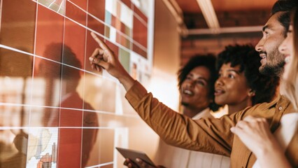 A candid moment of a diverse team in a brainstorming session pointing at various metrics displayed on a holographic interface while colorful visuals engage everyone in discussion.