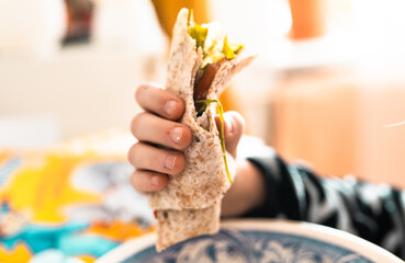 Hands with tortilla with vegetables closeup. Healthy snack for children and adults.