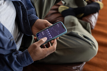 Over the shoulder view of man checking financial data with mobile banking app on a smartphone