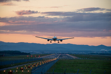 夕暮れの飛行場に着陸するジェット機
