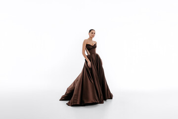 Beautiful young girl model in chocolate dress on white isolated background. Prom and evening...