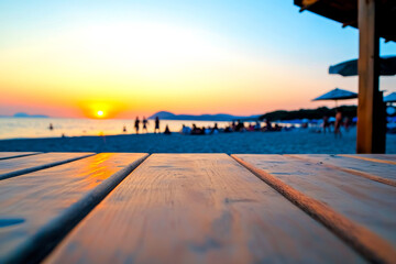 Fototapeta premium A serene beach sunset view with silhouetted figures in the background and a wooden deck in the foreground, capturing a tranquil evening atmosphere.