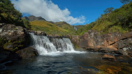 Fototapeta premium Waterfall cascading in Scottish Highlands, rainbow in background; nature tourism