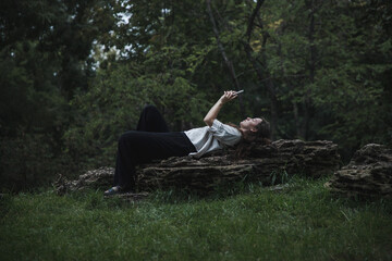 A girl is glued to her phone in nature. A girl can't relax without her phone. A girl reads the...