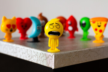 A yellow, humanoid emoji figure with an anxious expression takes center stage among a group of...
