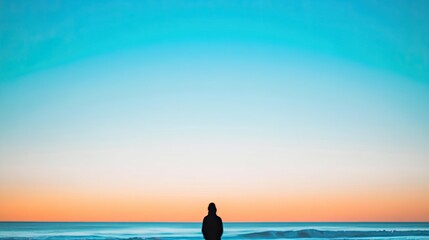 Fototapeta premium minimalistic image of tranquil beach at sunset featuring blurred silhouette of person in background