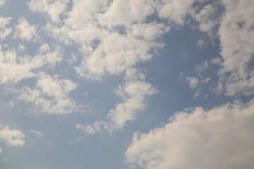 Obraz premium Fleecy clouds drift lazily across a pale blue sky, evoking a sense of peace