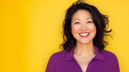 Fototapeta premium Smiling asian female adult against bright yellow background