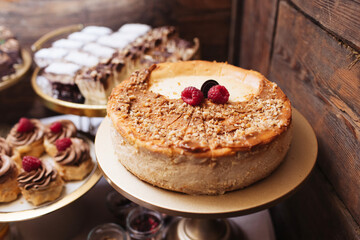 Rustic caramel cheesecake background. Wooden style bakery. Chocolate muffins on tray.Rich, creamy flavor of sweet treat. Closeup of delicious dessert with caramel drizzle. Round cake buffet selection.