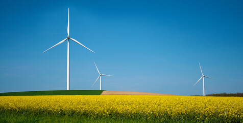 Windpark mit Windräder im gelben Rapsfeld, ländliches Panorama in Frankreich
