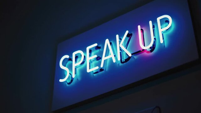 Neon sign glowing with powerful speak up message, blinking slowly against dark background and symbolizing courage, empowerment, and breaking silence for social awareness