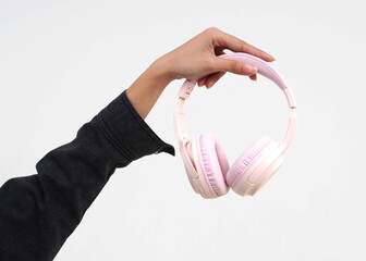 Hand wearing black denim jacket outer holding one pink wireless headphone object isolated on...