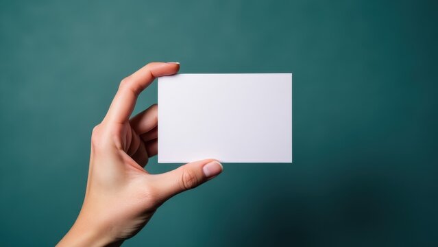 Hand holding business card mockup against a green background.