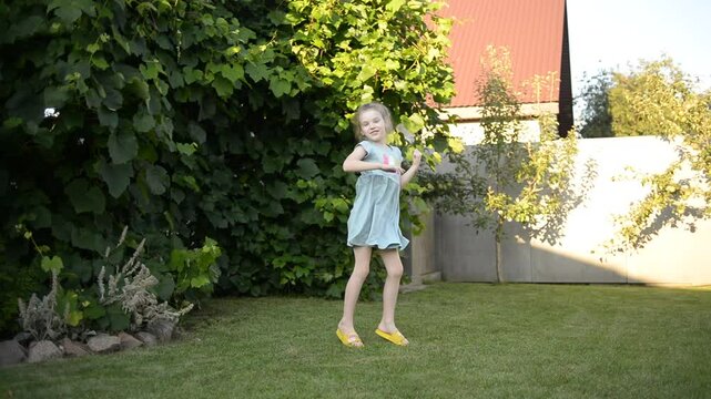 A joyful 7-year-old girl dancing happily in the yard of a house on a sunny summer day, expressing fun and freedom