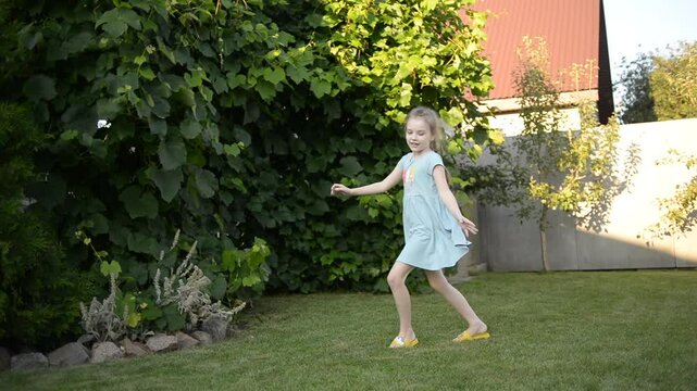A joyful 7-year-old girl dancing happily in the yard of a house on a sunny summer day, expressing fun and freedom