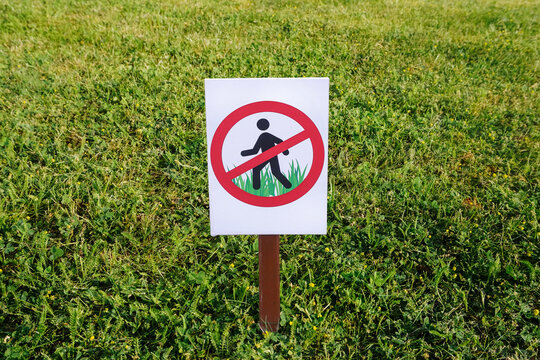 No walking on grass sign. Do not step on lawn warning symbol. Prohibition signpost on lawn. Forbidding harm to nature. Red and white road sign for environmental protection. Crossed out icon.