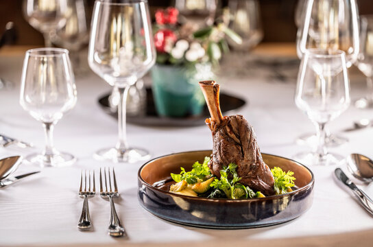 Confit leg of lamb on mashed potatoes with creamy kale, demi glace sauce and herbs