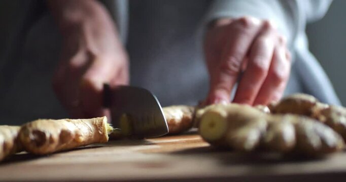 Female Hands Cutting Ginger with a Knife on a Board for Making Lemonade. Tea or Cocktail Ingredients. Ginger Root. Close-up