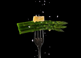 Green asparagus spears, topped with melting butter an sprinkled with salt .on a fork