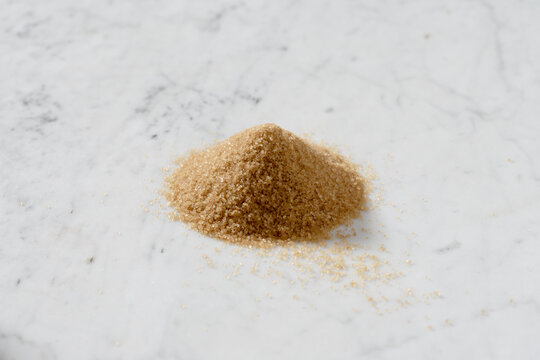Heaps of brown cane sugar on a marble slab